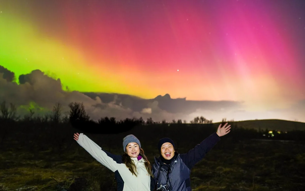 A small group watching a green aurora on an open plain in Iceland