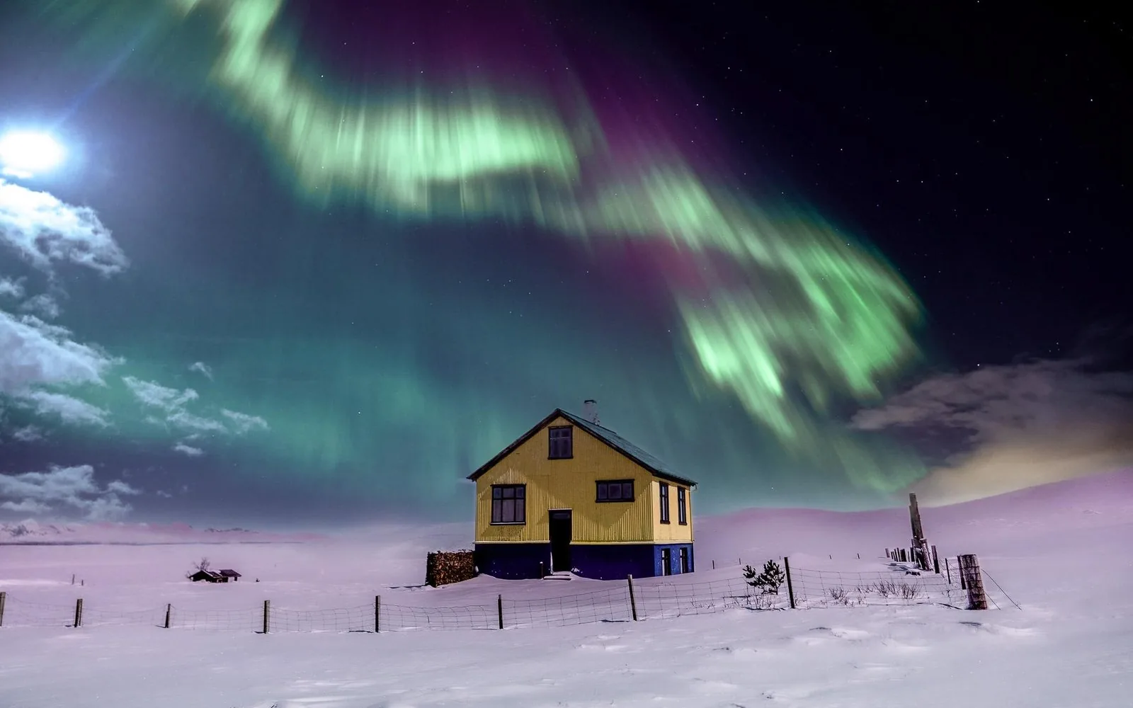A green aurora over a lone house in the snow outside Reykjavik
