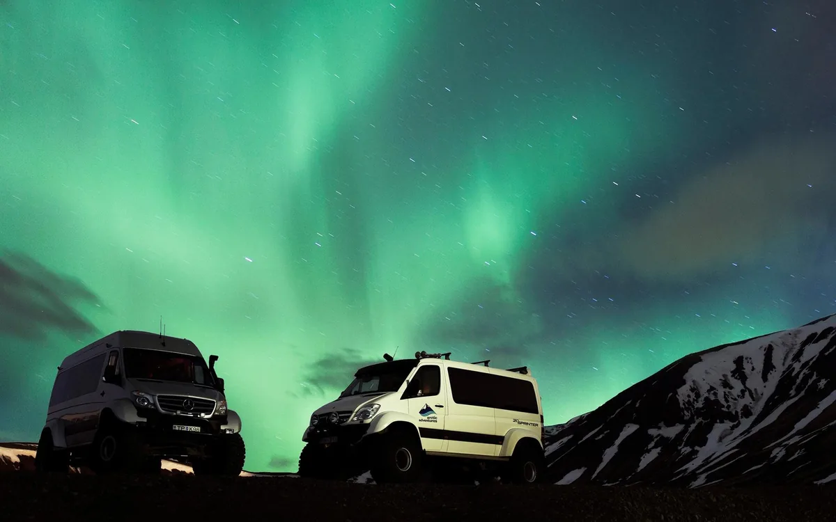 A super jeep parked under a green aurora