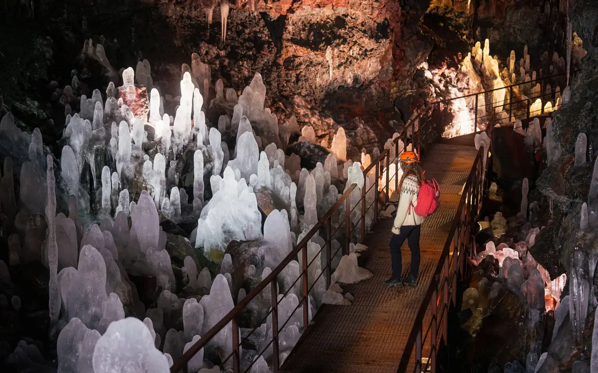 A lit lava tunnel with visitors on a walkway