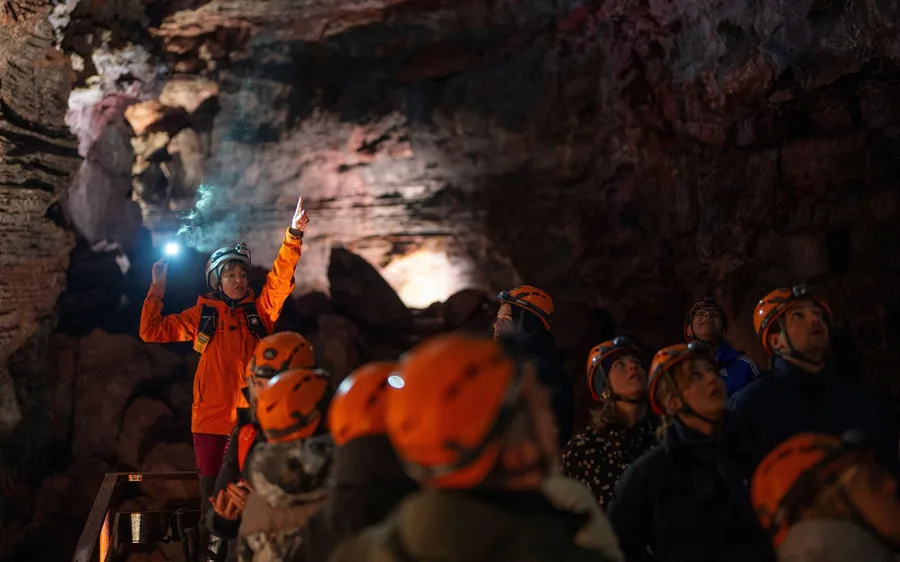 A lit lava tunnel with visitors on a walkway